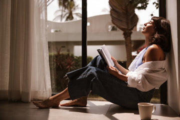 Relaxed woman embracing slow living, simple daily habits at home, showing how restful routines and 'lazy' self-care habits can boost mental wellness.