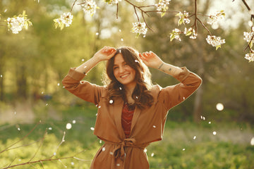 Smiling woman in nature focusing on the good, practicing mindfulness, positivity, and intentional living for emotional wellness.